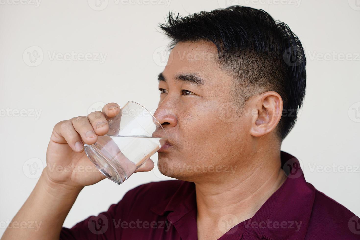 asiatique homme est en buvant l'eau de verre. concept boisson l'eau pour santé, boisson après repas, médicaments , pendant le journée ou après avoir en haut dans le Matin. santé se soucier, soulager la soif photo