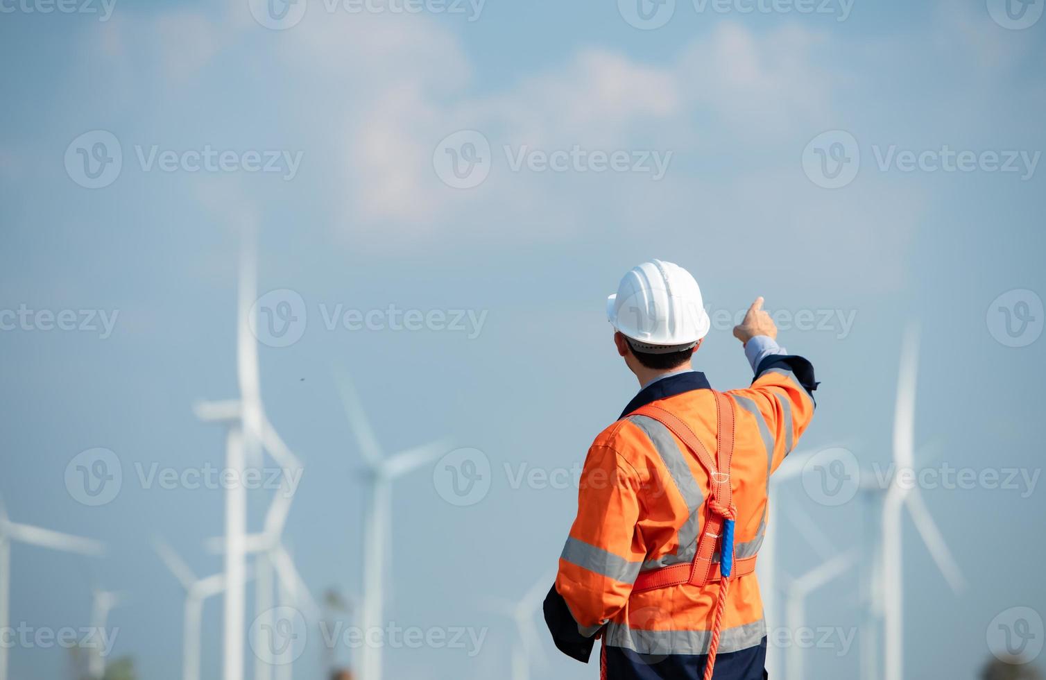 ingénieur à Naturel énergie vent turbine site avec une mission à prendre se soucier de grand vent turbines utilisation une walkie talkie à communiquer avec une collègue travail sur Haut de le vent turbine. photo