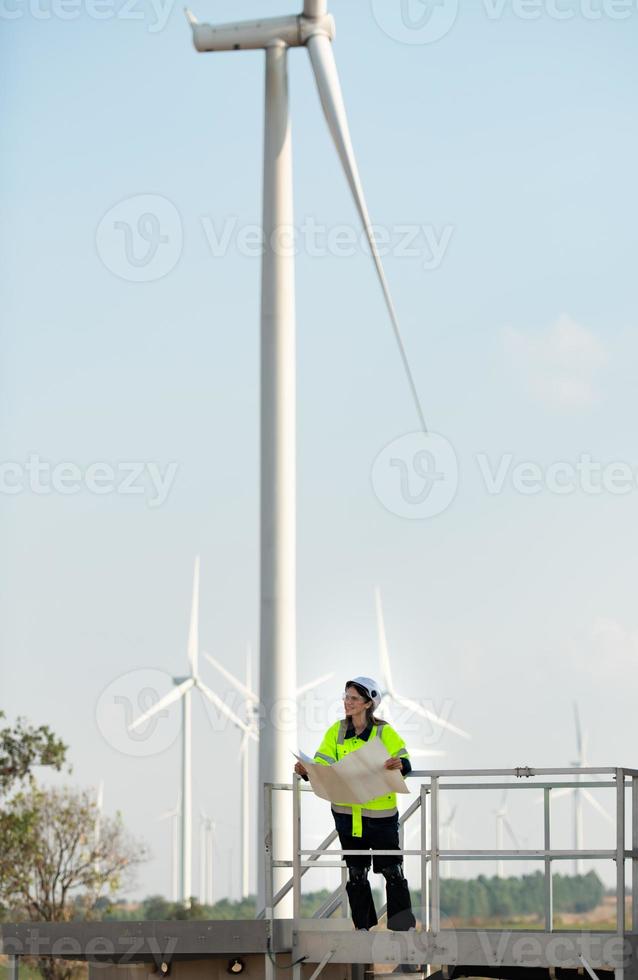 portrait de femelle ingénieur à Naturel énergie vent turbine site avec le mission de étant responsable pour prise se soucier de grand vent turbines photo