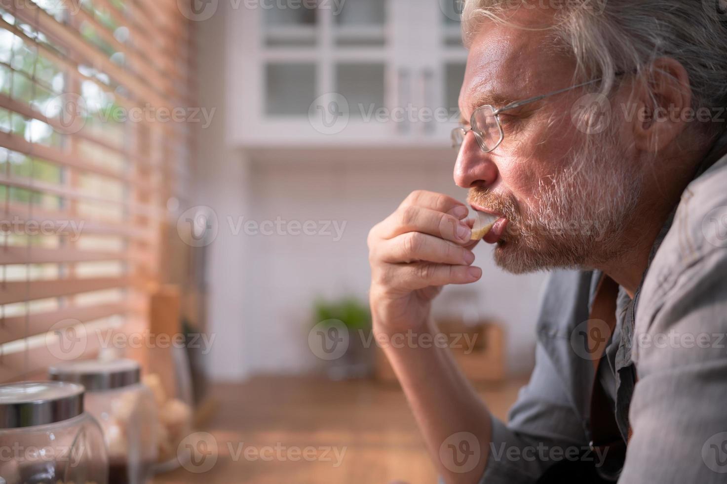 grand-père dans le cuisine avec Naturel lumière, en train de préparer pour le jours dîner pour le famille. photo