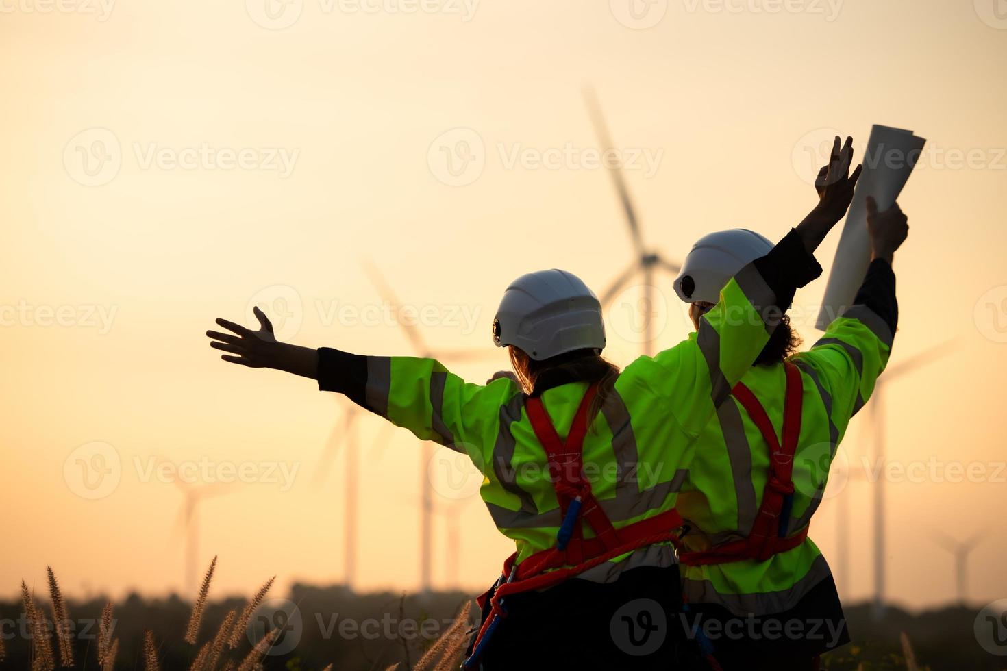 ingénieurs travail sur vent fermes pour renouvelable énergie sont dans charge de massif vent turbine entretien. supporter et regarder le le coucher du soleil tandis que encourageant chaque autre à Achevée le travail de le journée. photo