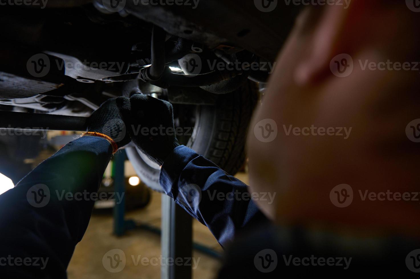 le concept de voiture service, voiture entretien et garantie réparation dans une réparation magasin. une technicien chèques le châssis pour roue alignement de une voiture levé sur une ascenseur dans une atelier garage photo