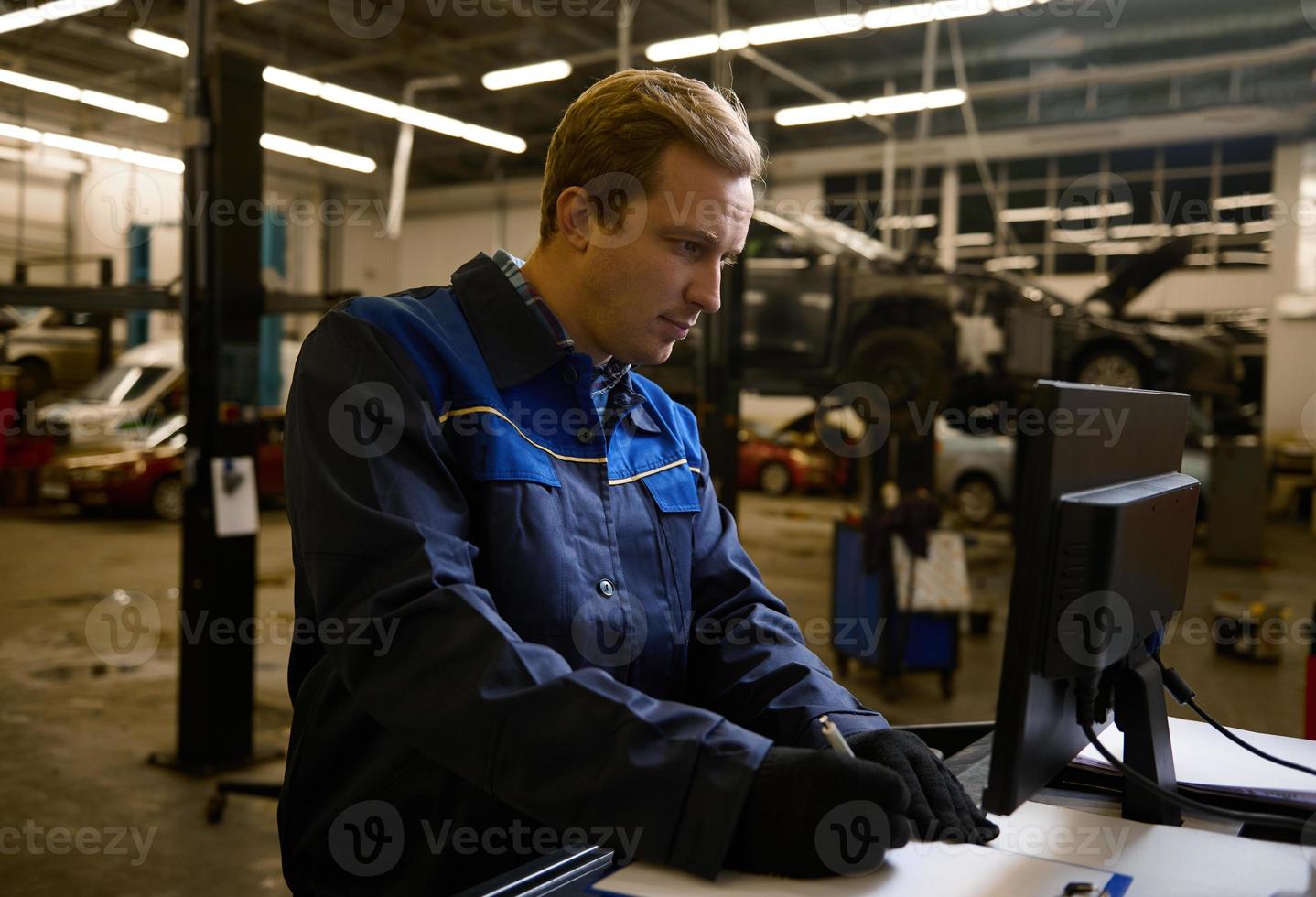 concentré auto mécanicien technicien voiture ingénieur l'écriture liste de contrôle sur presse-papiers et travail sur moniteur tandis que entretien une voiture dans le auto un service photo