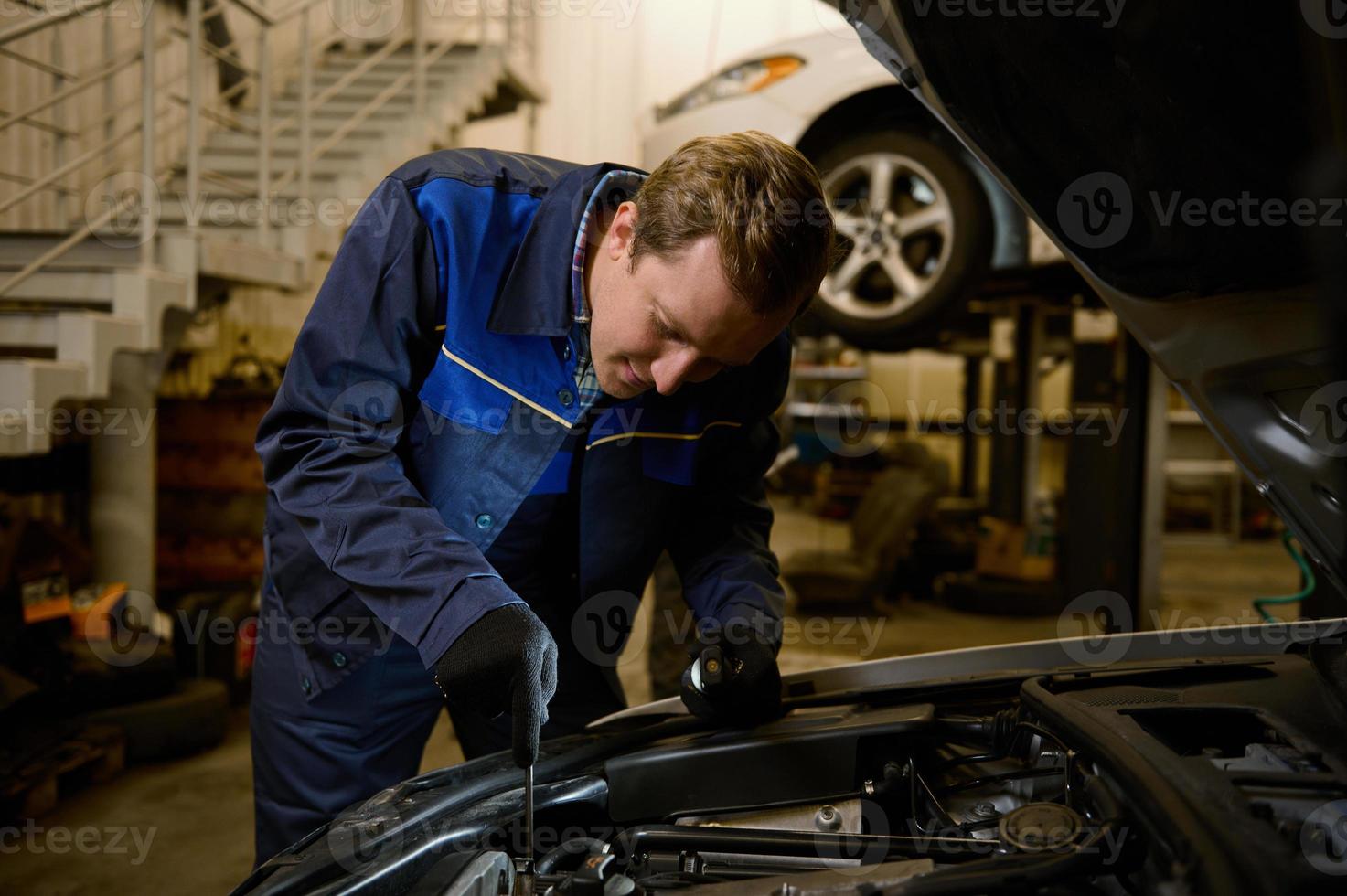 mécanicien vérification et réparer voiture moteur, technicien inspecter le moteur de un voiture avec ouvert capuche dans le réparation magasin. voiture entretien, consumérisme, gens et la main d'oeuvre concept photo