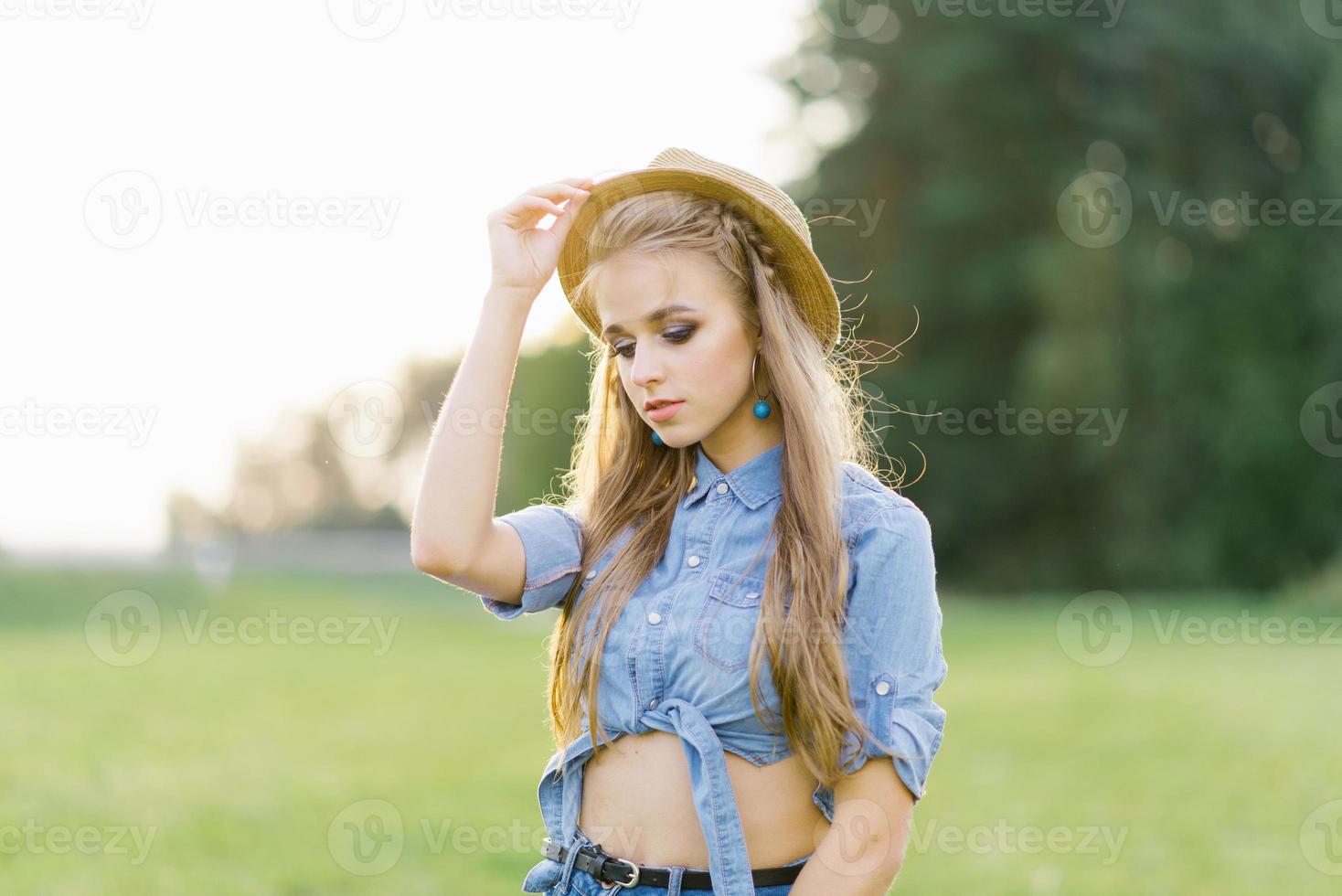 élégant Jeune femme dans une chapeau des promenades en plein air dans été photo
