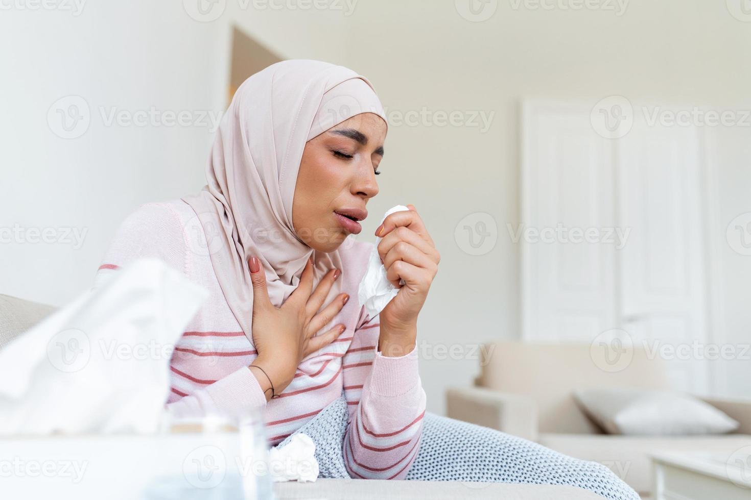 arabe femme est ayant grippe . malade avec une rhinite femme avec hijab a égouttage nez. femme étant malade ayant grippe mensonge sur canapé. photo