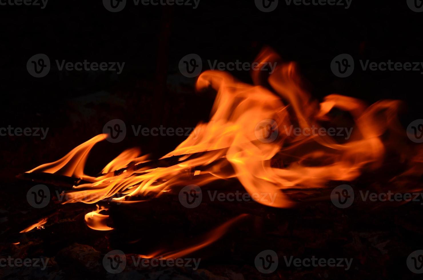 brûlant bois journaux dans le nuit. flou lumière. brillant rouge Feu. la nature photo. photo