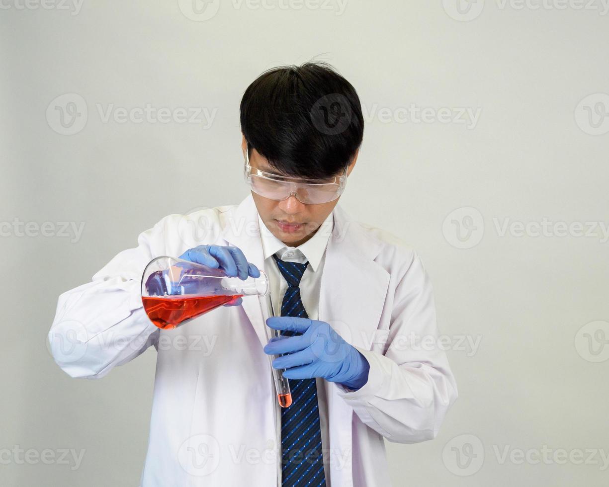 asiatique homme étudiant scientifique ou médecin dans réactif mélange laboratoire dans une science recherche laboratoire avec tester tubes de divers tailles. sur le sol dans laboratoire chimie laboratoire blanc Contexte. photo