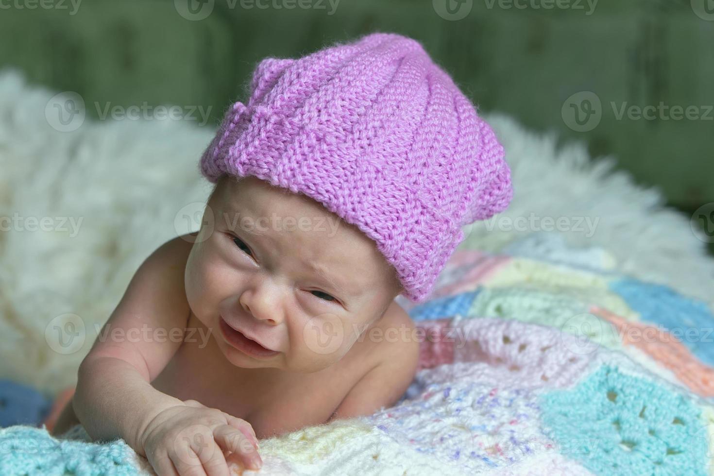 nouveau née bébé avec marrant affronter. peu bébé dans rose casquette est pleurs. photo