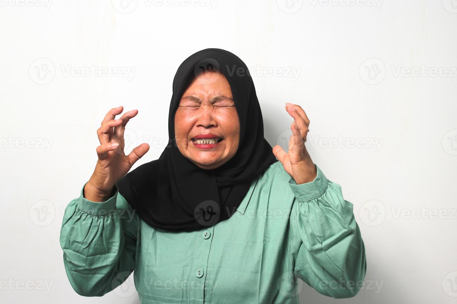 en colère milieu vieilli asiatique femmes portant hijab élevé sa main tandis que à la recherche à caméra photo