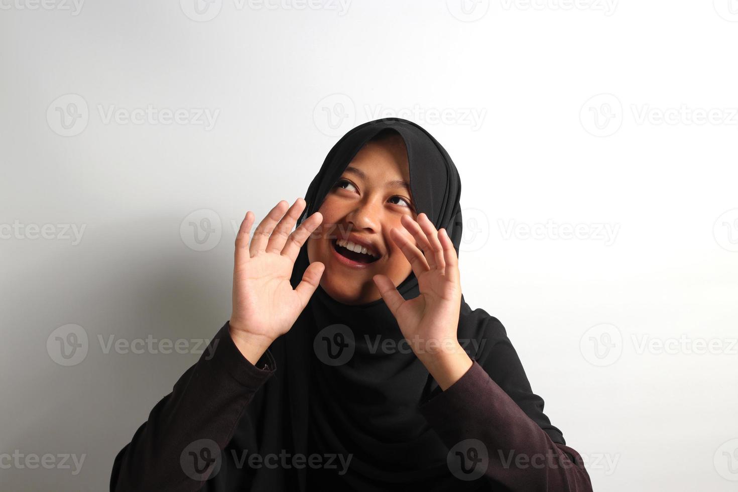 de bonne humeur Jeune asiatique fille dans hijab en criant bruyamment récit à propos bien nouvelles isolé sur blanc Contexte. photo