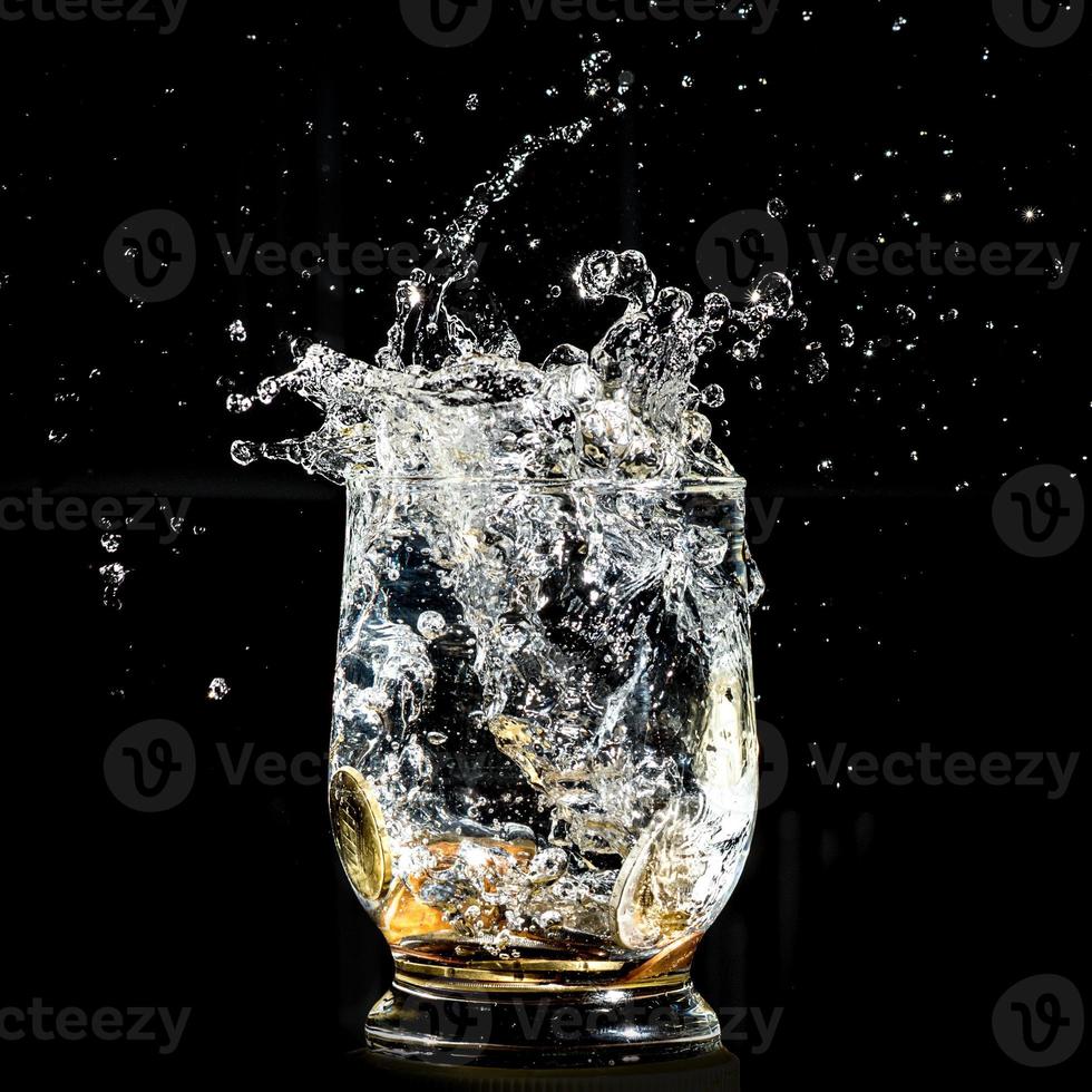 pièces tombant éclaboussant dans un verre à eau photo