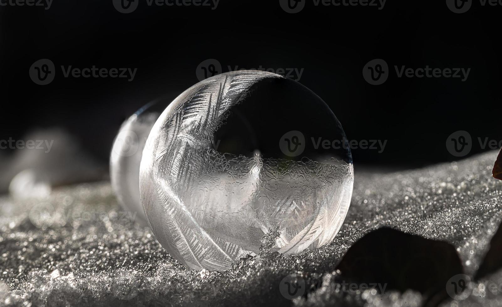 Détail d'une bulle de savon gelée sur un sol enneigé pendant la nuit photo