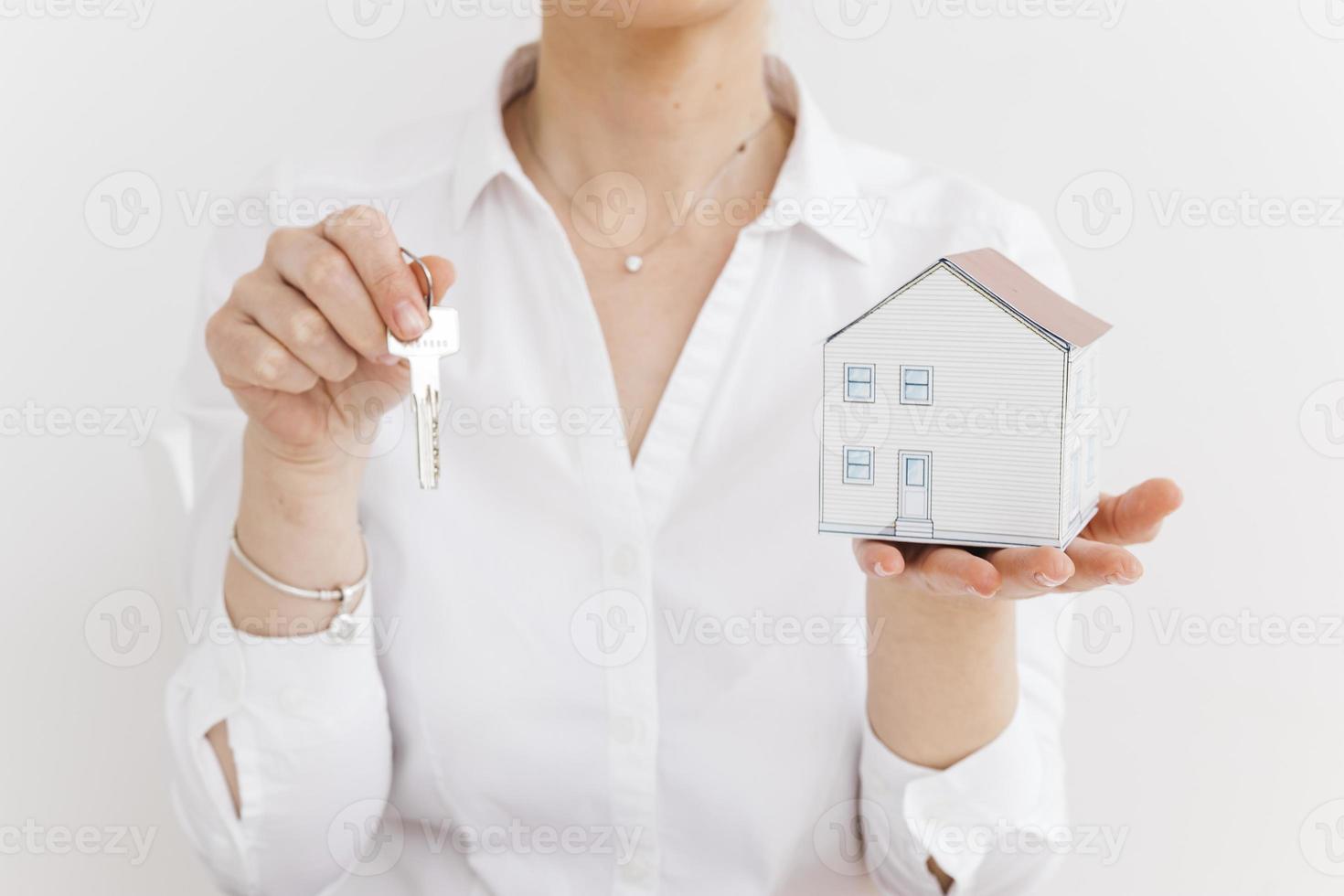 Woman holding key sand mall papier maison sur fond blanc photo