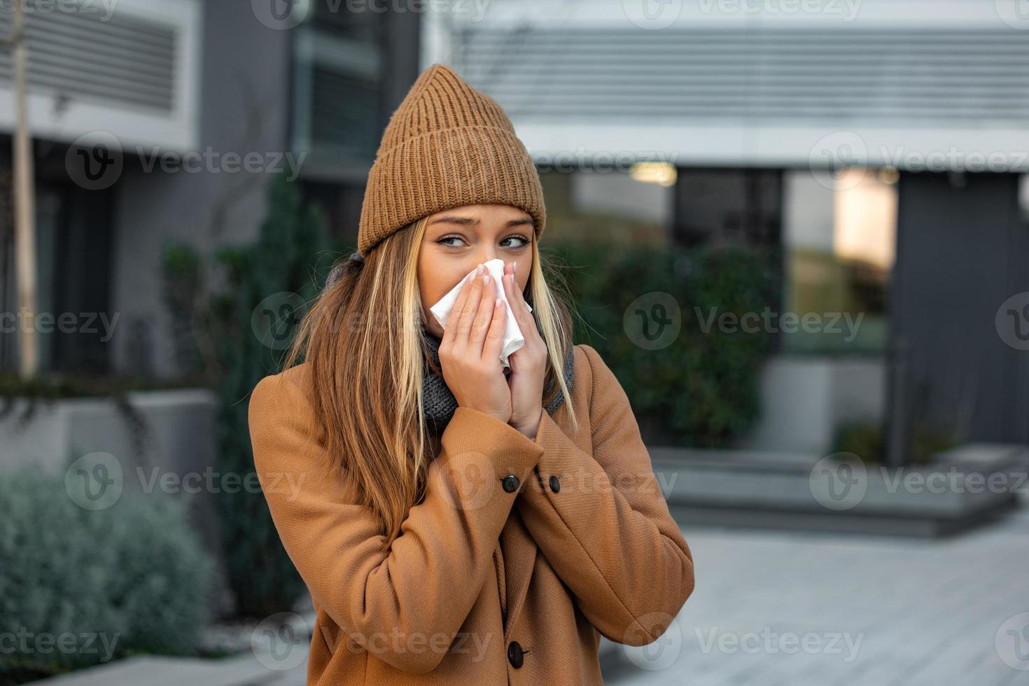 mauvais magnifique Jeune femme éternuements et soufflant nez dans serviette de table. malade femme d'affaires dans affaires style éternuement à rue. mauvais pour la santé employé. Extérieur. virus symptômes. du froid maladie. photo