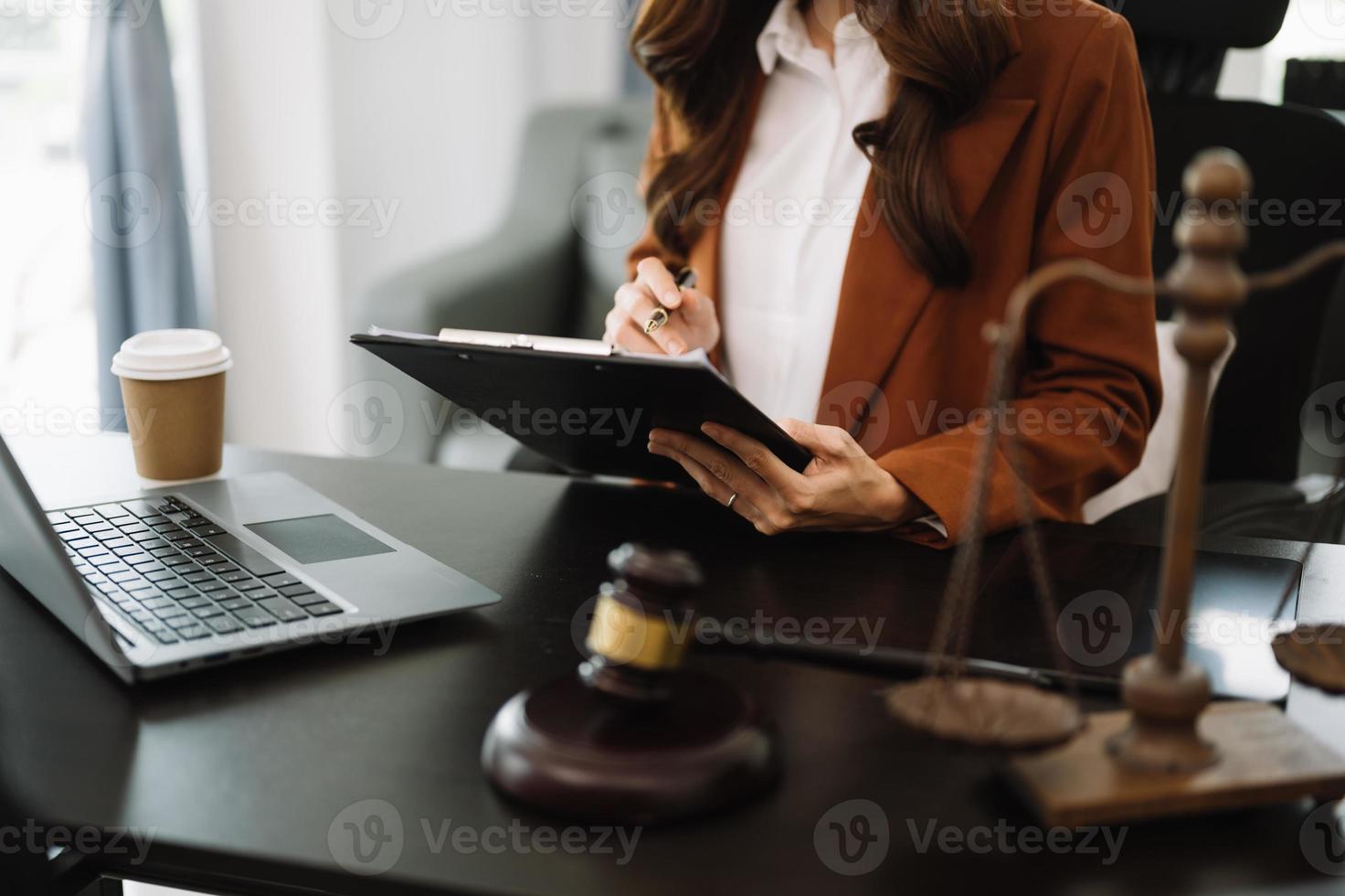 concept de justice et de droit. juge masculin dans une salle d'audience le marteau, travaillant avec un téléphone intelligent et un ordinateur portable et une tablette numérique sur une table en bois photo