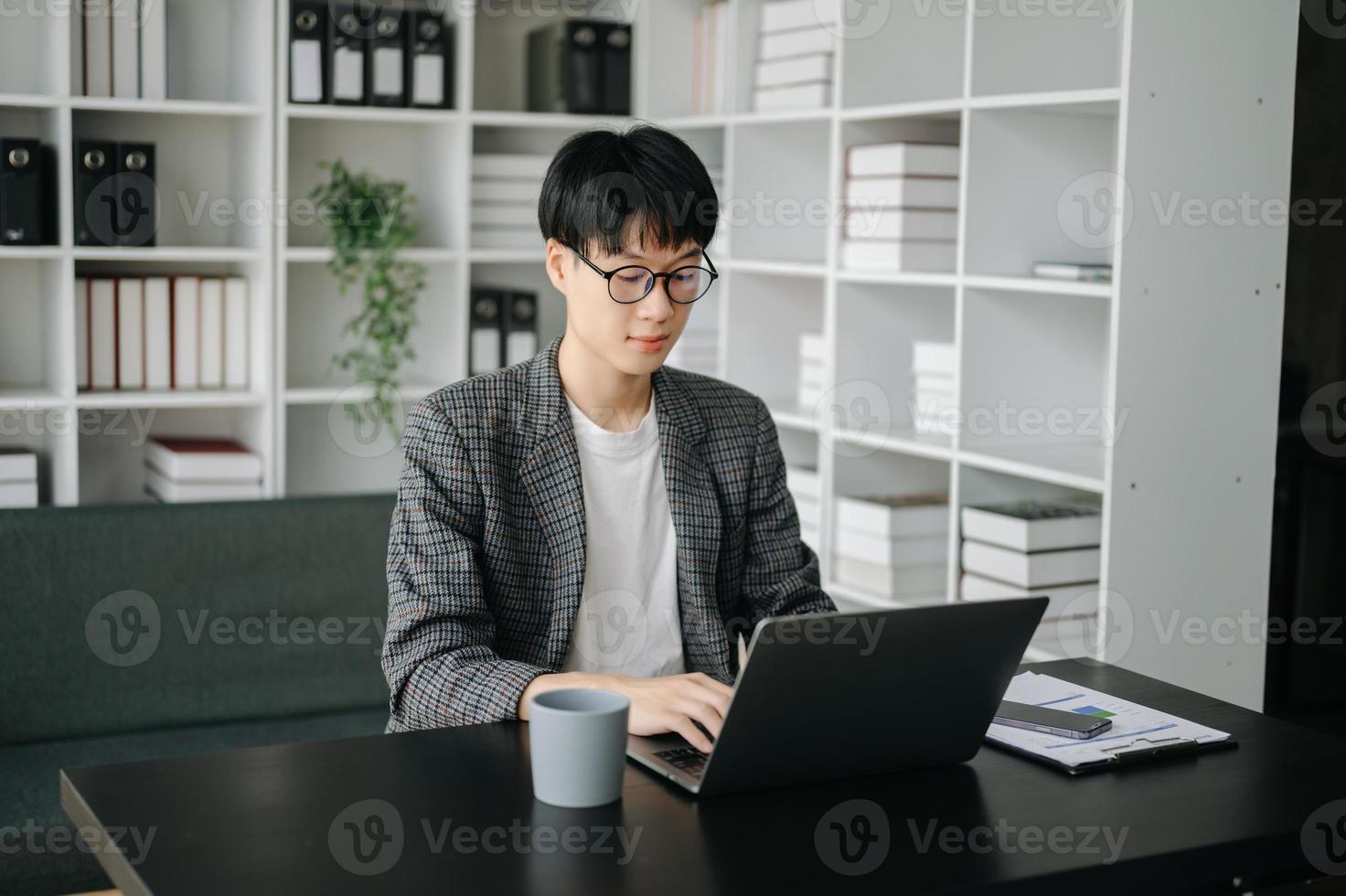 Jeune affaires homme exécutif directeur à la recherche à portable en train de regarder en ligne séminaire en ligne formation ou ayant virtuel réunion vidéo conférence Faire marché recherche travail dans bureau. photo