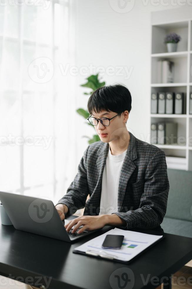 Jeune affaires homme exécutif directeur à la recherche à portable en train de regarder en ligne séminaire en ligne formation ou ayant virtuel réunion vidéo conférence Faire marché recherche travail dans bureau. photo