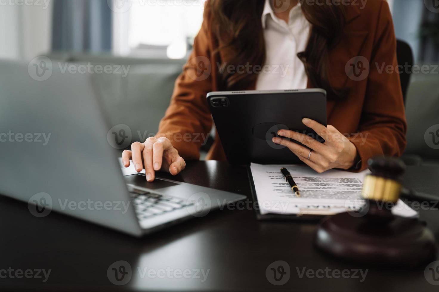 concept de justice et de droit. juge masculin dans une salle d'audience le marteau, travaillant avec un téléphone intelligent et un ordinateur portable et une tablette numérique sur une table en bois photo