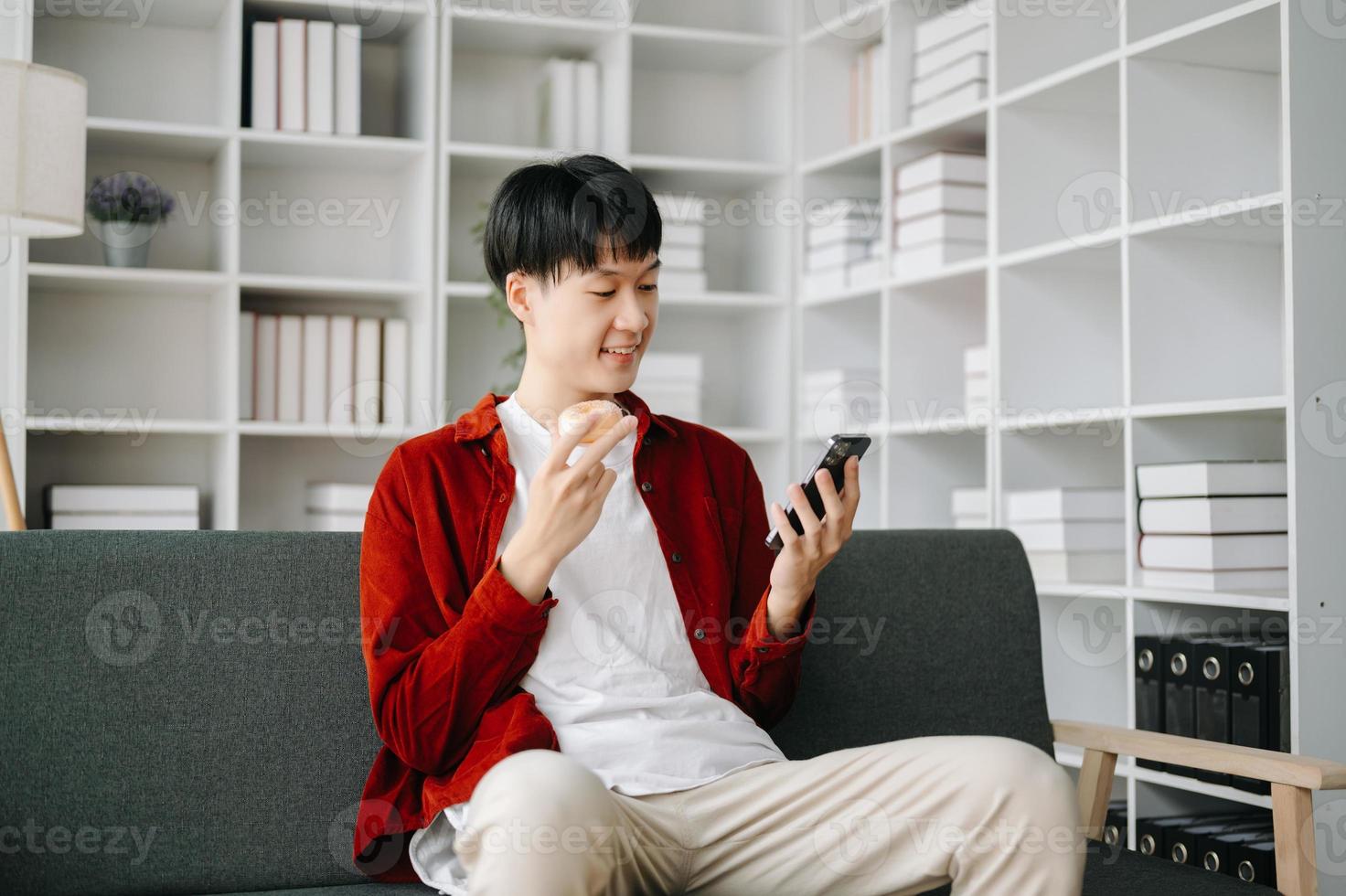 Jeune attrayant asiatique homme souriant en pensant Planification l'écriture dans carnet de notes, tablette et portable travail de Accueil à Accueil Bureau photo