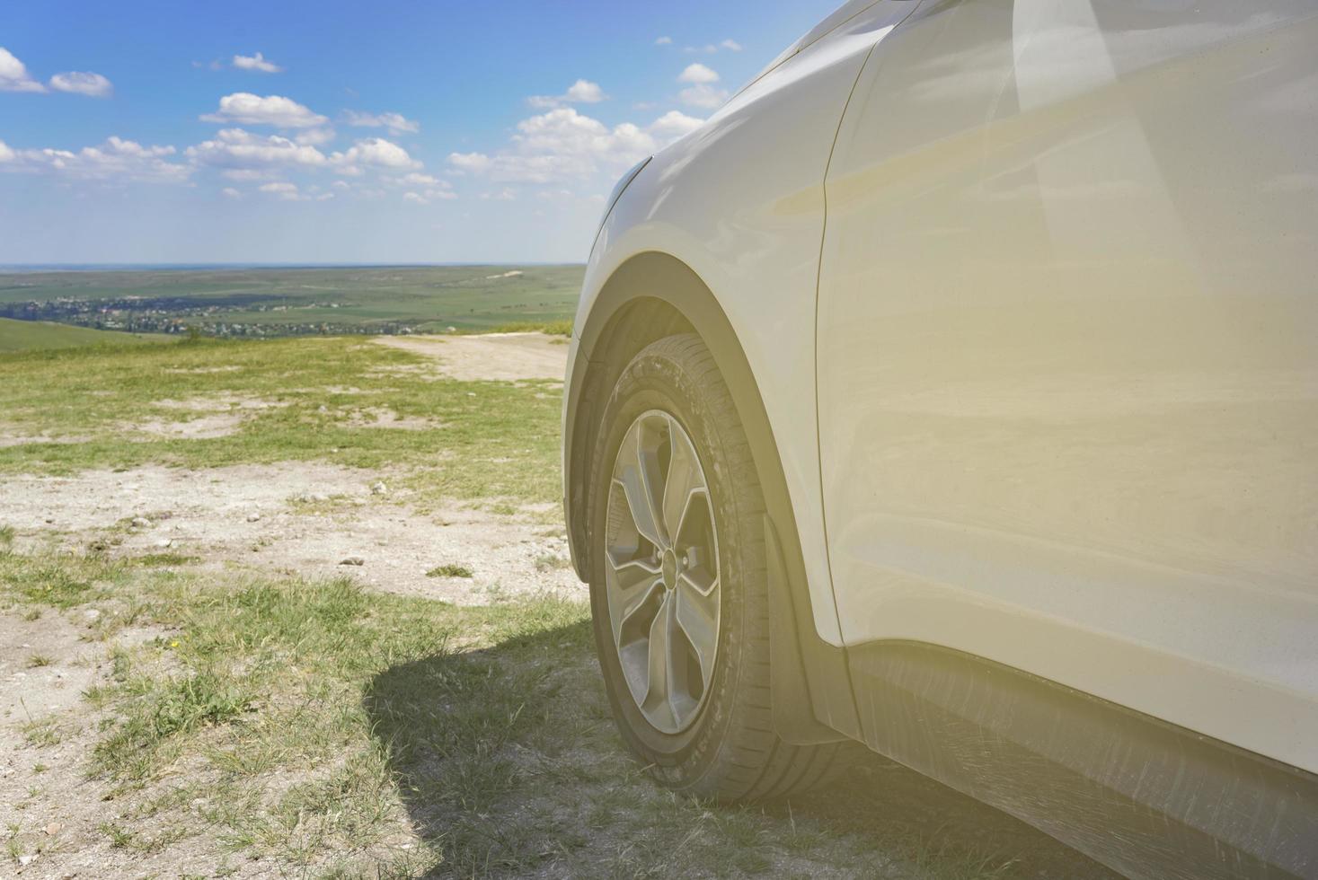 partie d'un SUV blanc avec une roue sur un fond de paysage naturel. photo