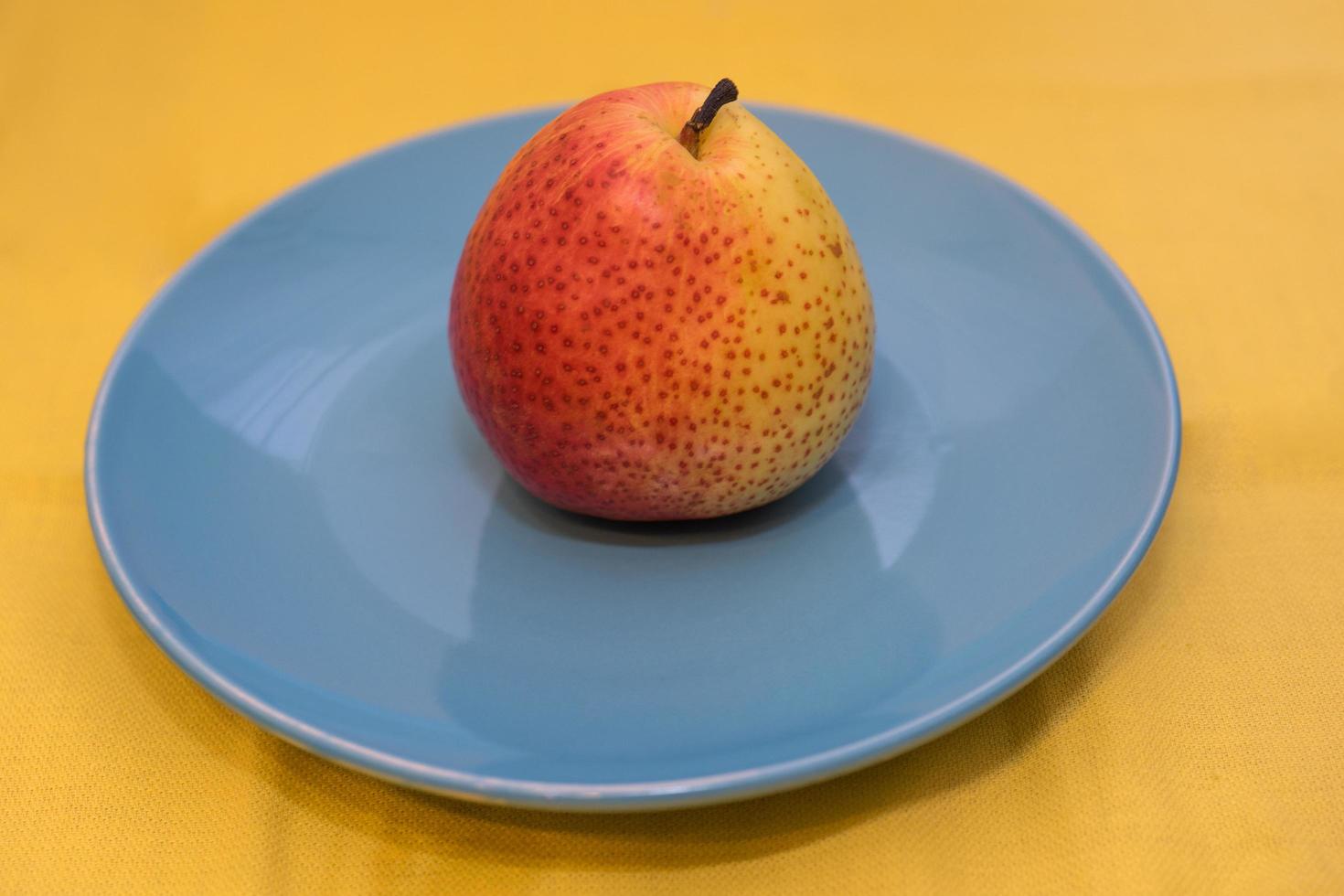 Poire juteuse et lumineuse sur plaque en céramique bleue debout photo