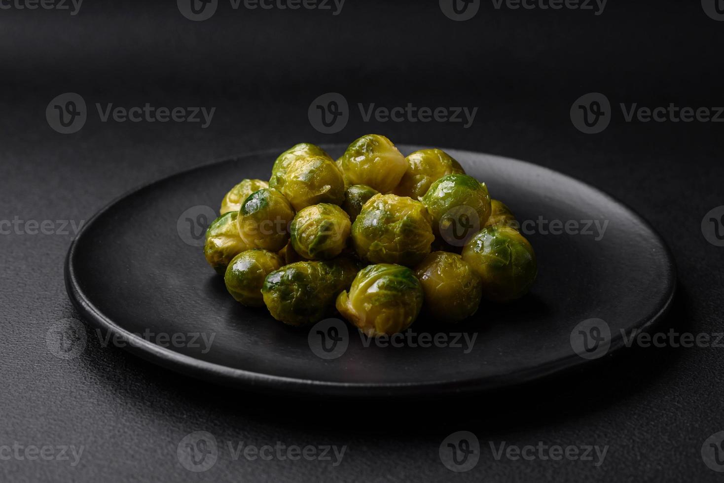 délicieux bouilli Bruxelles choux sur une céramique assiette sur une foncé béton Contexte photo