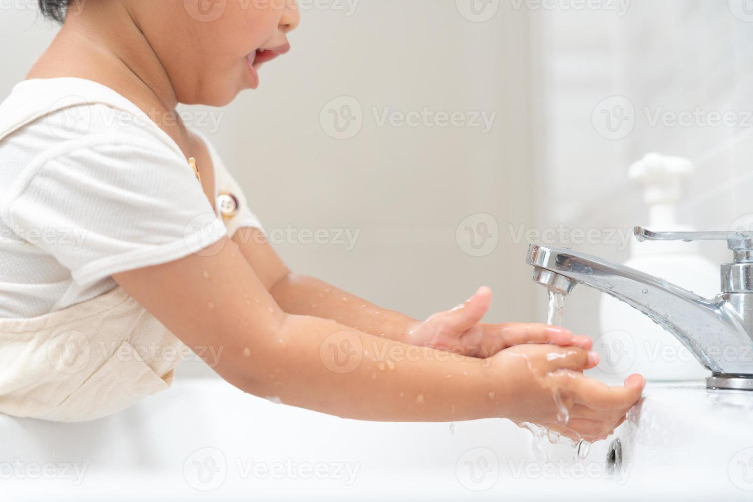 peu enfant mains laver avec savon bulles et rincer avec nettoyer l'eau à prévenir et Arrêtez le propager de germes après retour à maison, virus ou COVID-19 [feminine. bien santé et bien personnel hygiène, virus, les bactéries photo