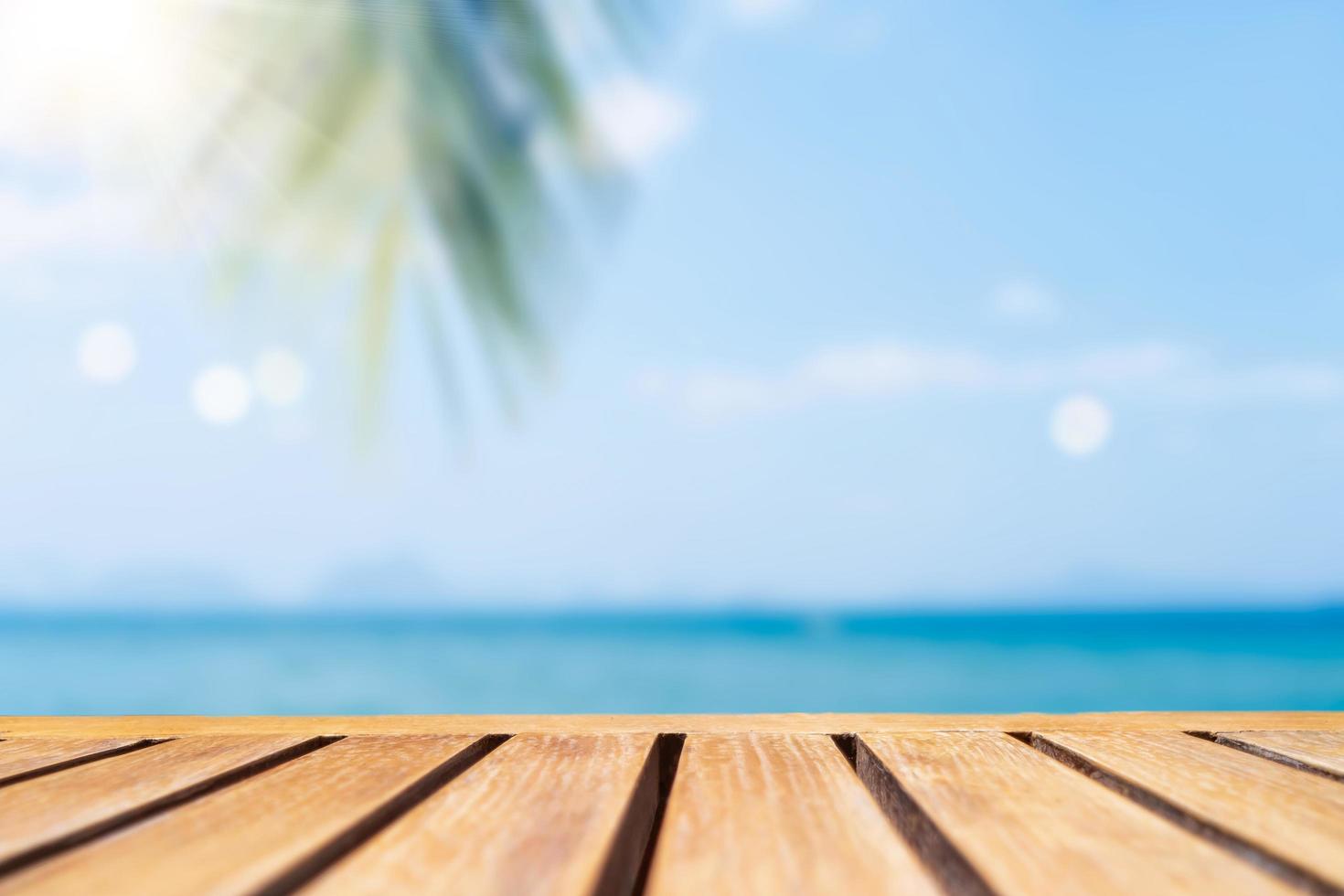 mise au point sélective de la vieille table en bois avec une belle plage floue avec des palmiers tropicaux pour afficher votre produit. photo