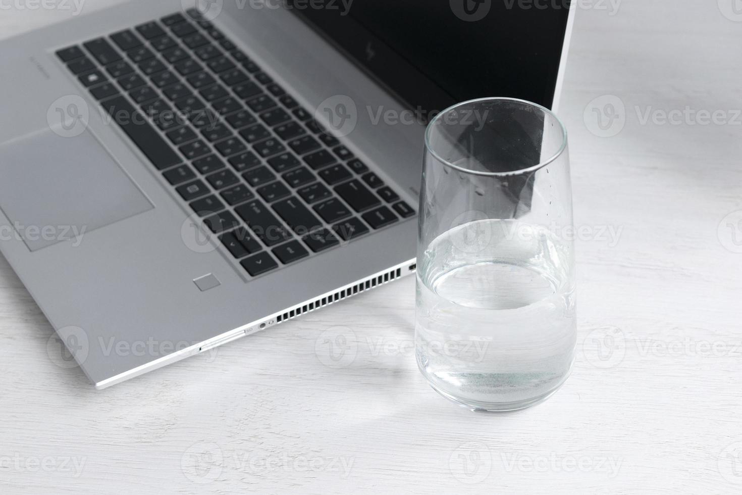 femme travail avec portable tandis que en buvant verre de l'eau sur une table à maison. photo