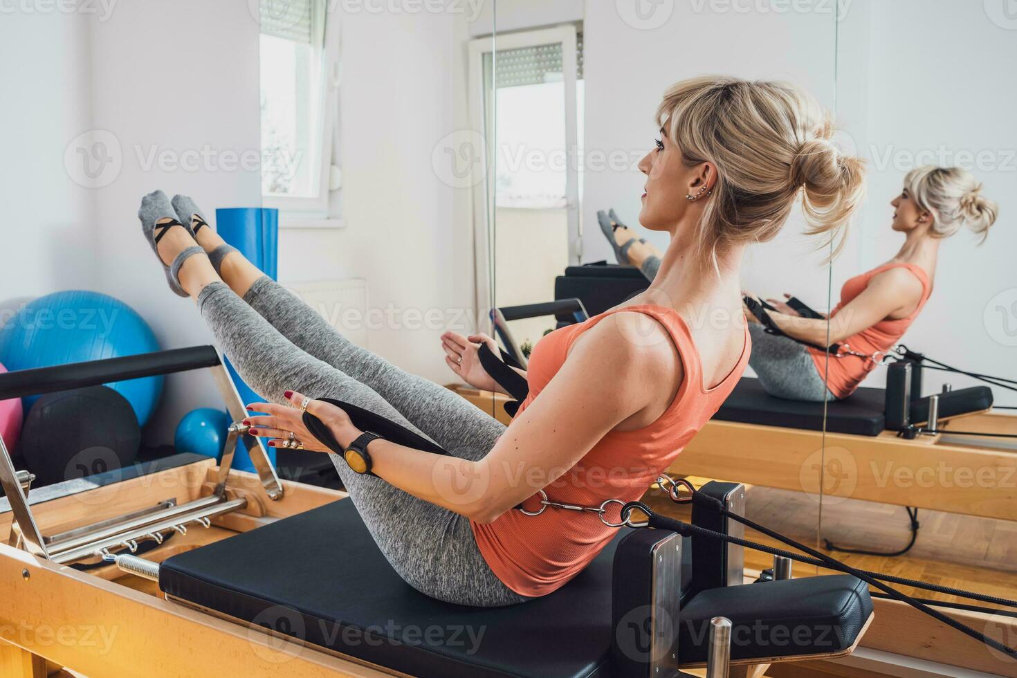 blond femme est exercice sur pilates réformateur lit dans sa maison. photo