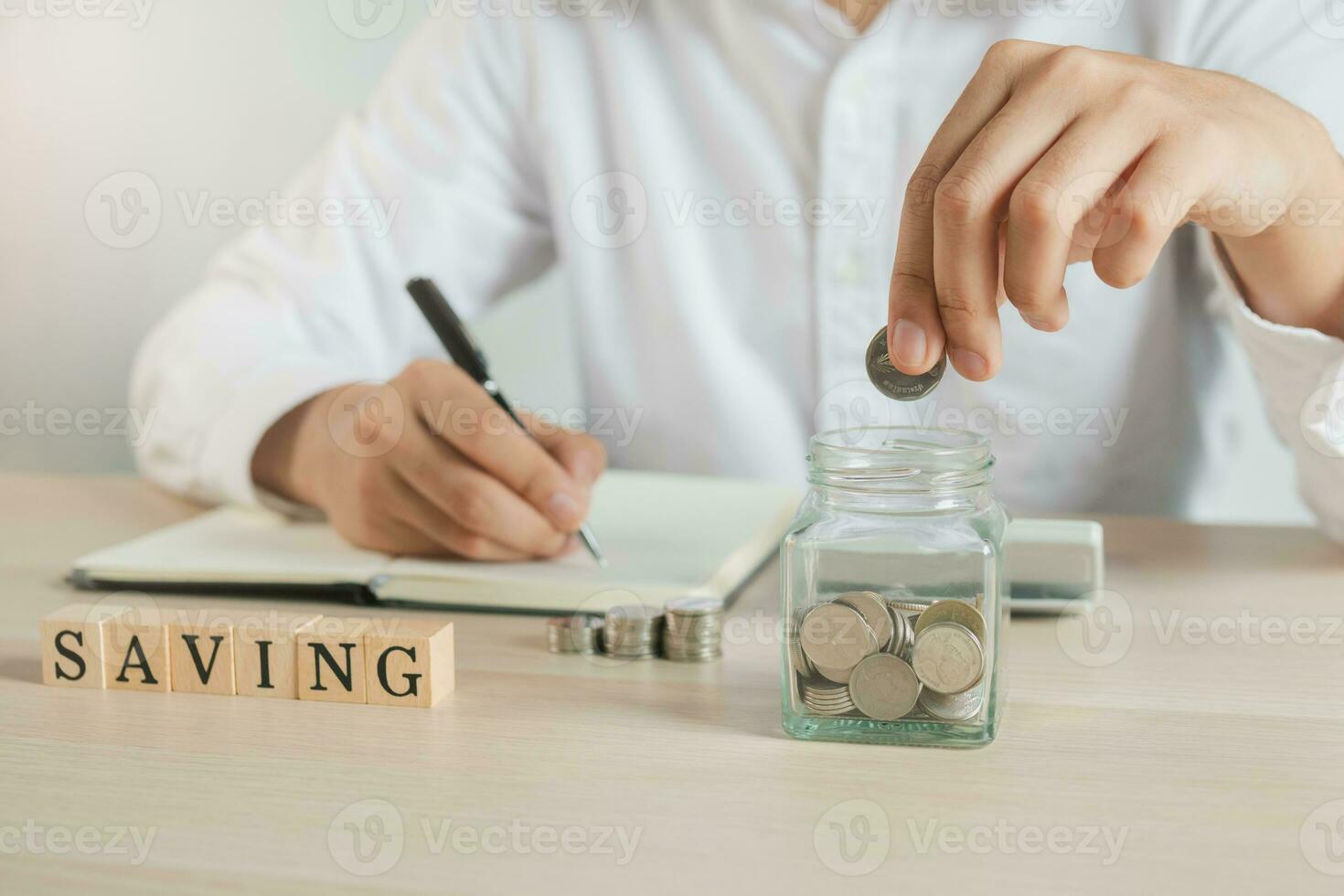 proche en haut main de Jeune asiatique homme d'affaire met une pièce de monnaie dans le pot à calculer et financier des plans à dépenser assez argent sur le sien le revenu pour économie argent. photo