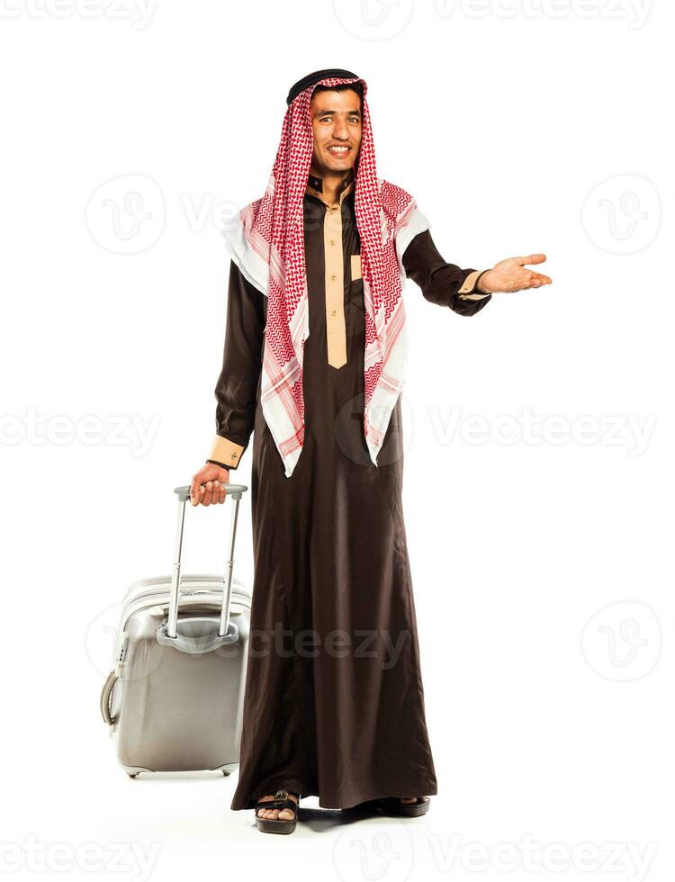 Jeune souriant arabe avec une valise isolé sur blanc photo