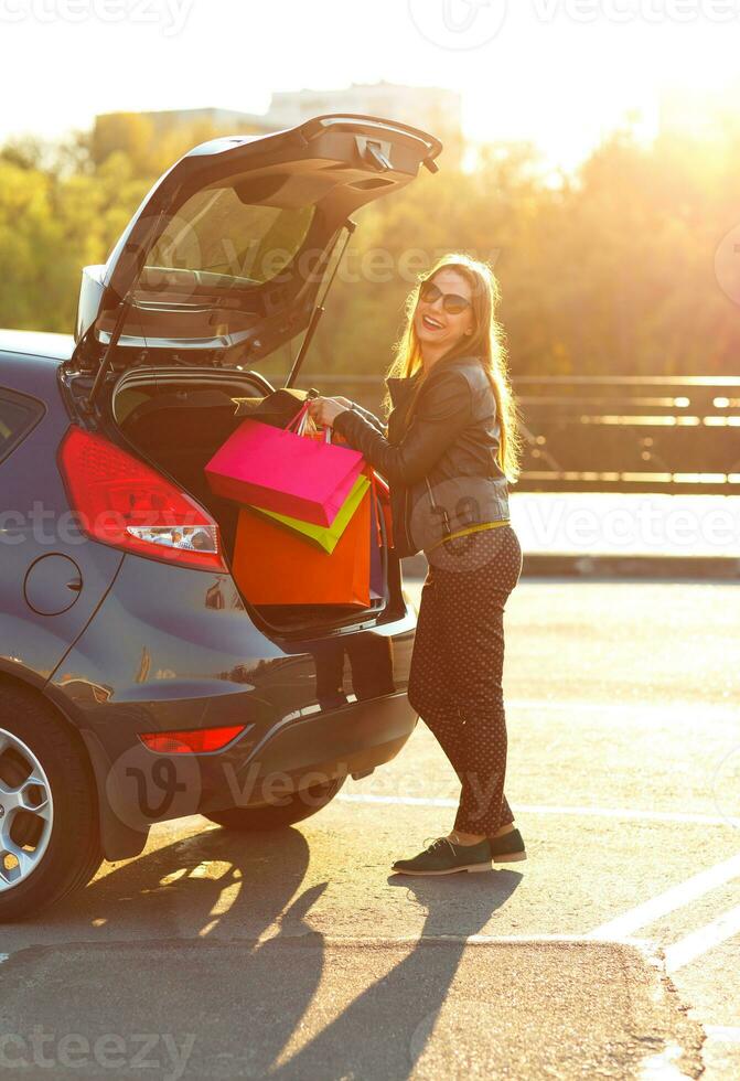 caucasien femme en mettant sa achats Sacs dans le voiture tronc photo