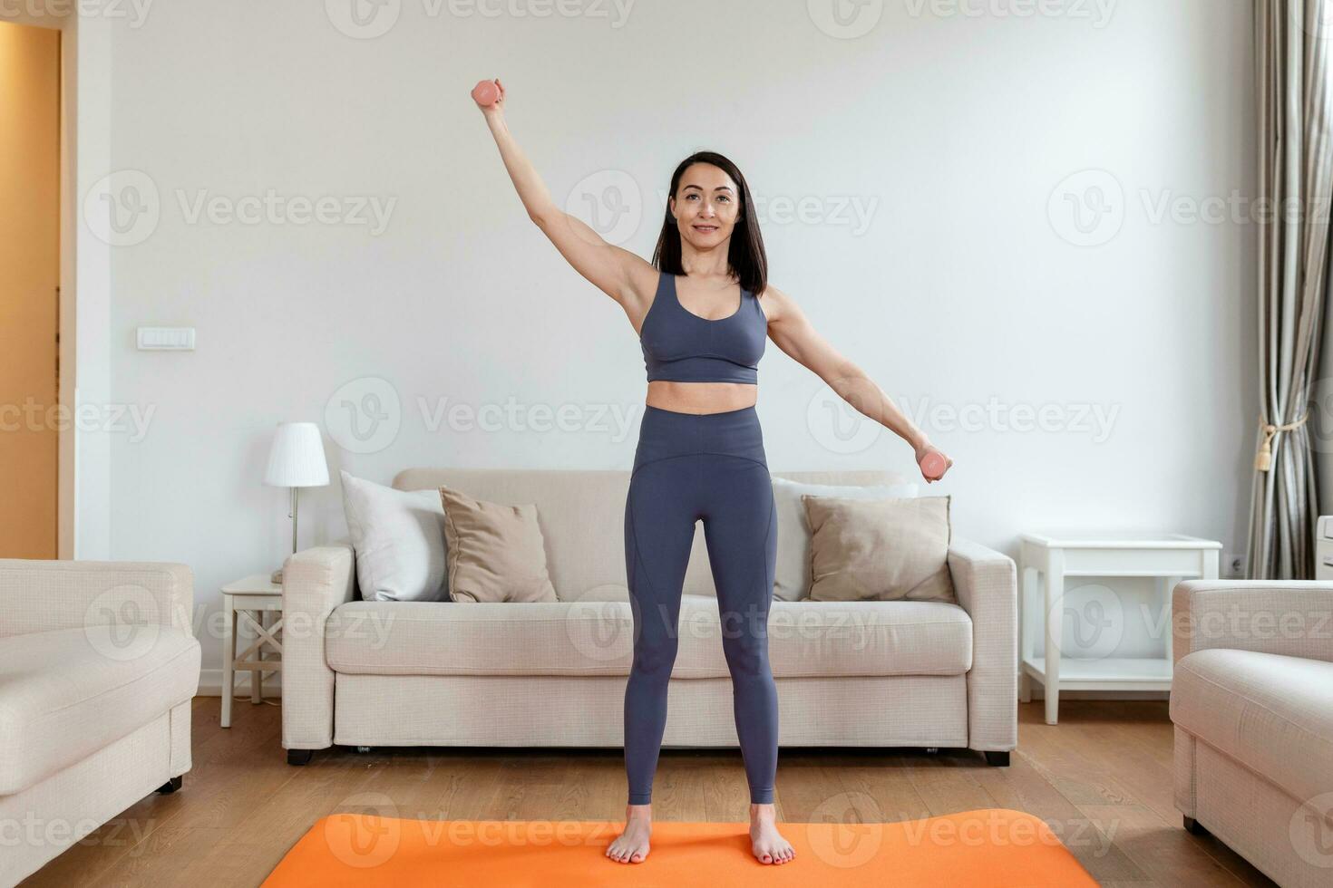 asiatique femme exercice avec haltères à maison. content femelle Faire bras faire des exercices en utilisant haltères photo