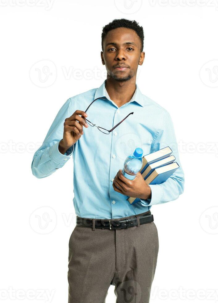 africain américain Université étudiant avec livres dans le sien mains permanent sur blanc photo