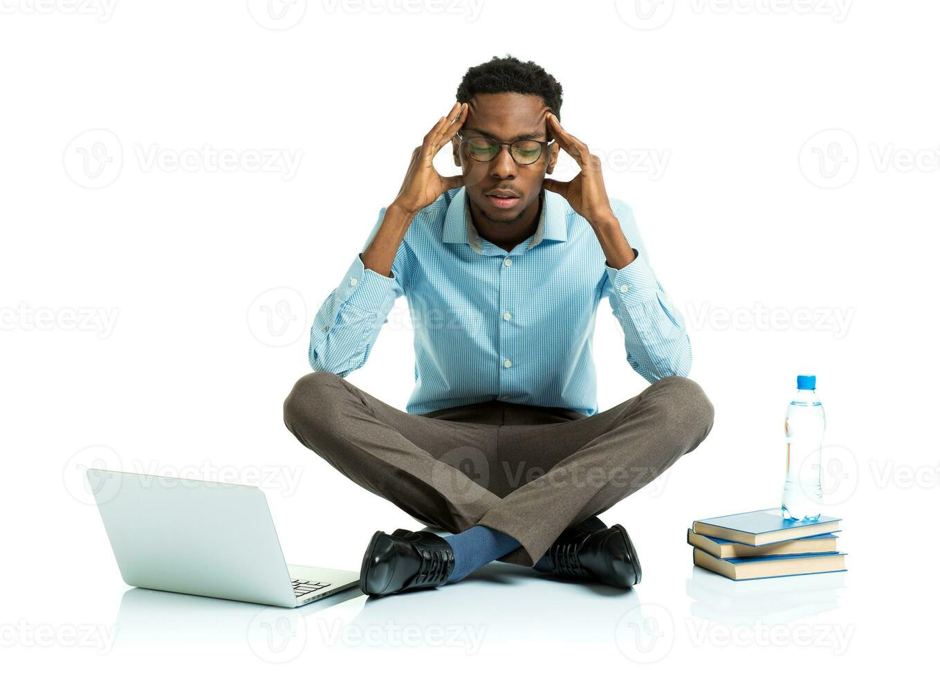 africain américain Université étudiant dans stress séance avec ordinateur portable, livres et bouteille de l'eau sur blanc photo