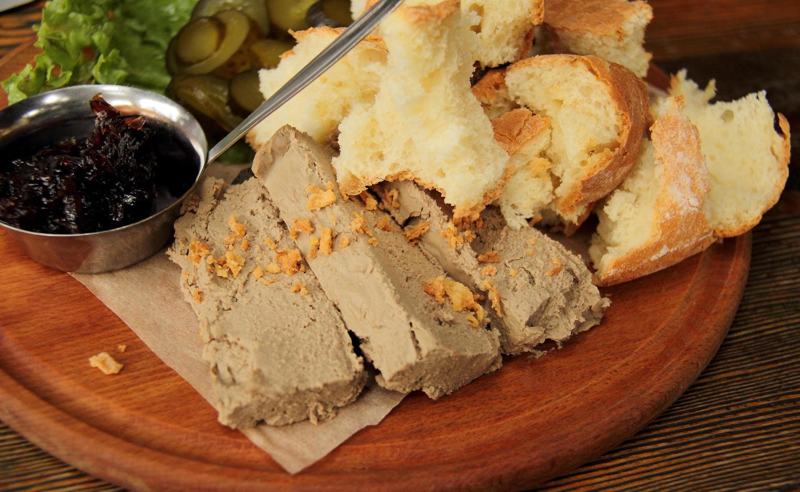 pâté avec du pain et des cornichons sur un plateau en bois photo