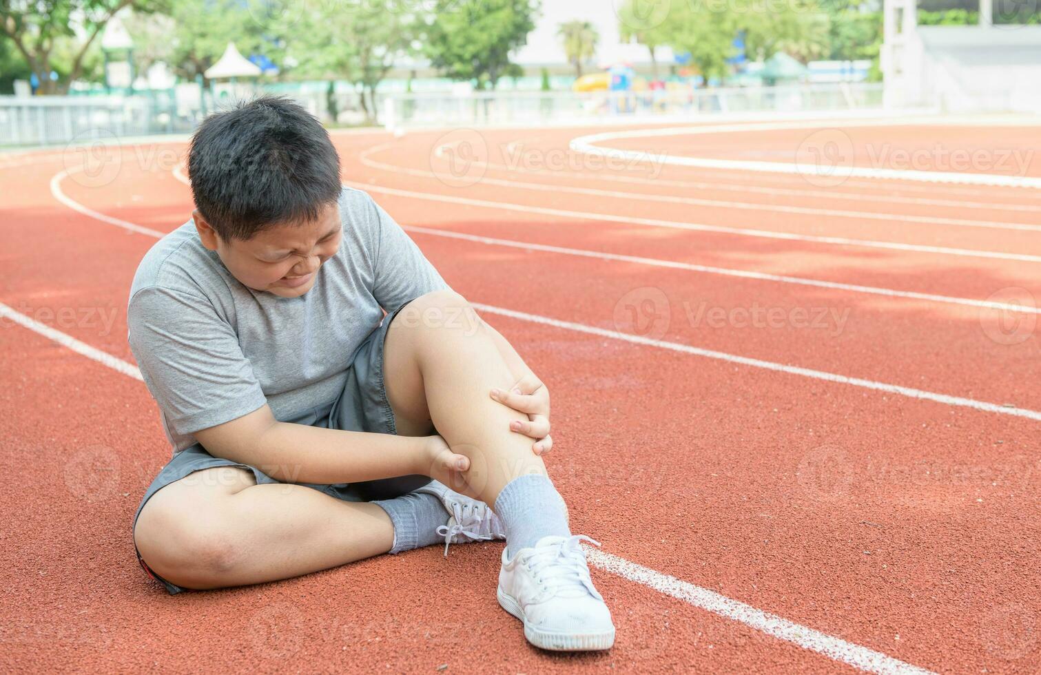 asiatique graisse garçon en portant le sien des sports jambe blessure. muscle douloureux photo