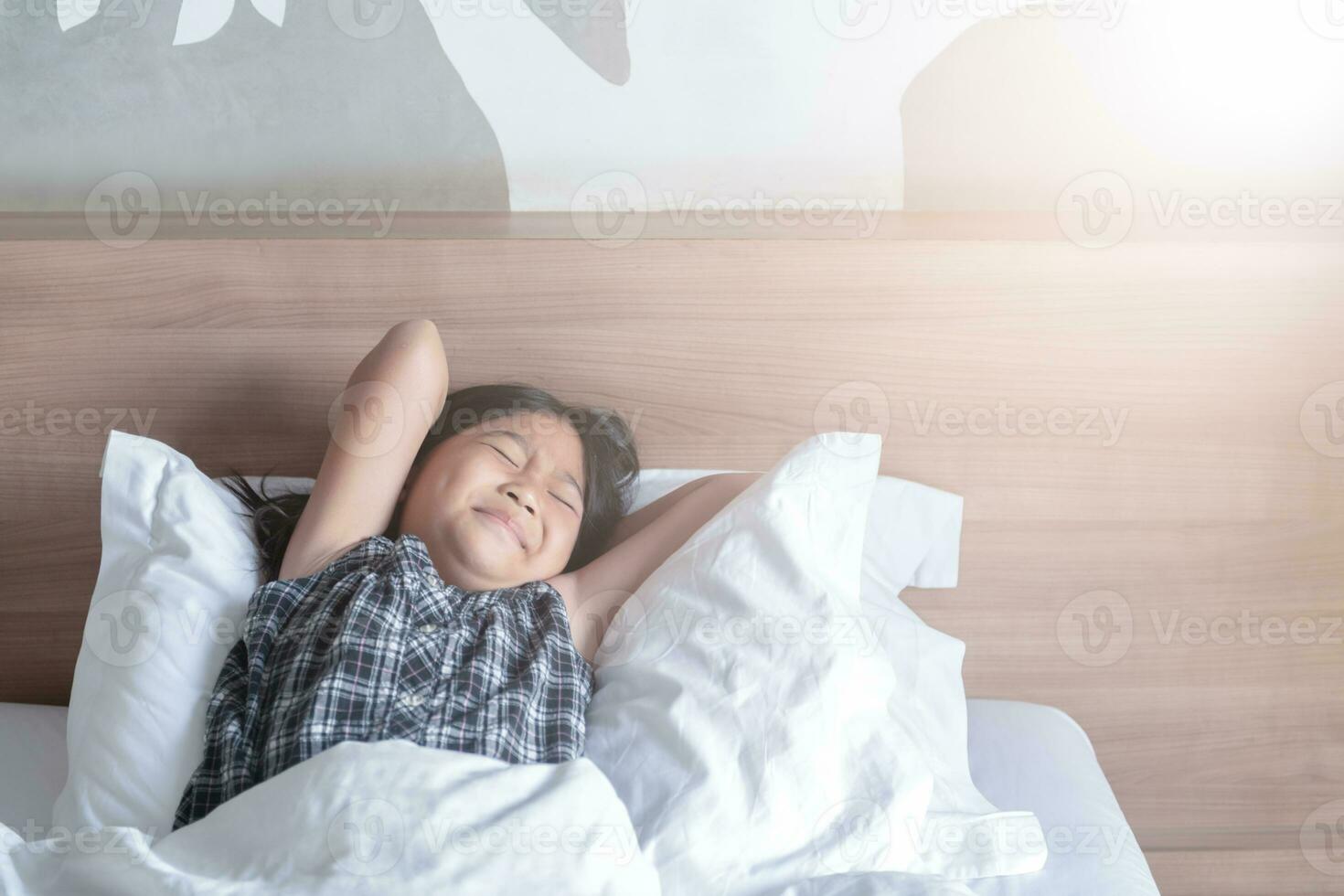 fille se réveille en haut et élongation sur lit dans matin, photo