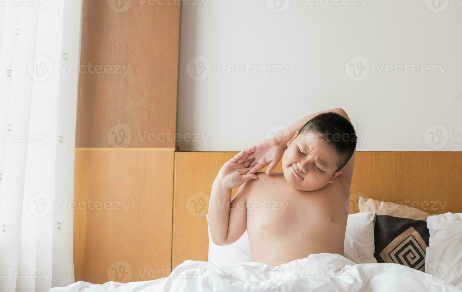 obèse garçon se réveille en haut et élongation sur lit photo