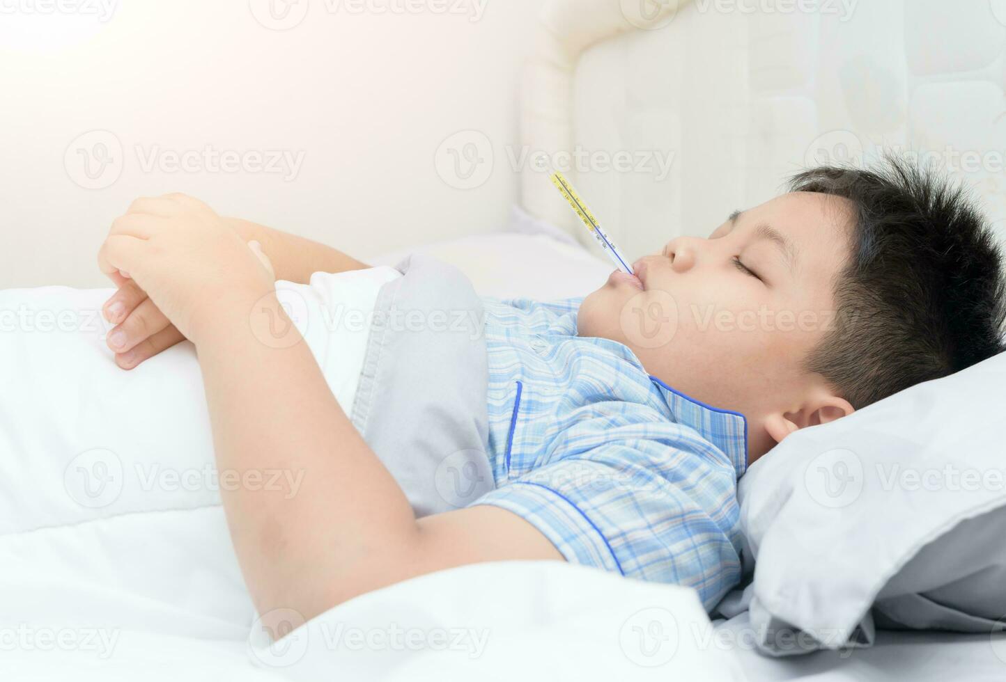 malade garçon avec thermomètre sommeil sur lit photo