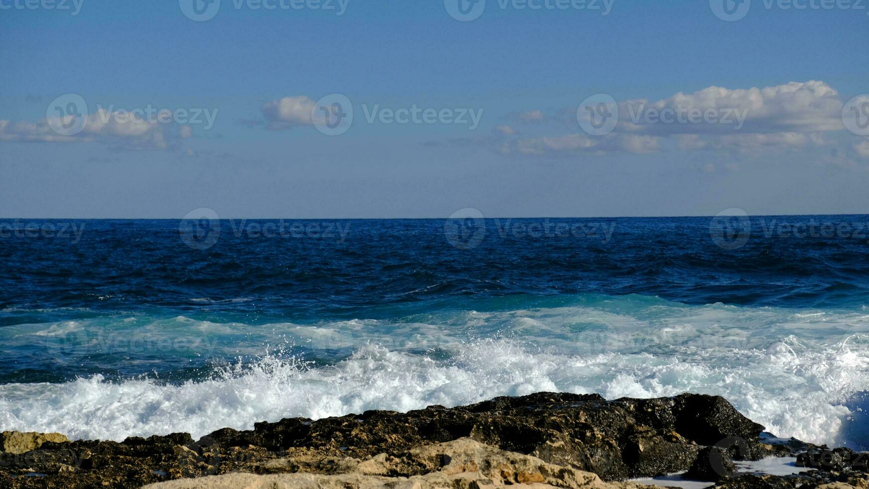 bleu mer vague et blanc mousse et éclaboussure. pierre plage sur île de Malte, non sablonneux plage. été vacances frontière Cadre concept. tropical île vacances toile de fond. touristique Voyage bannière conception modèle. photo