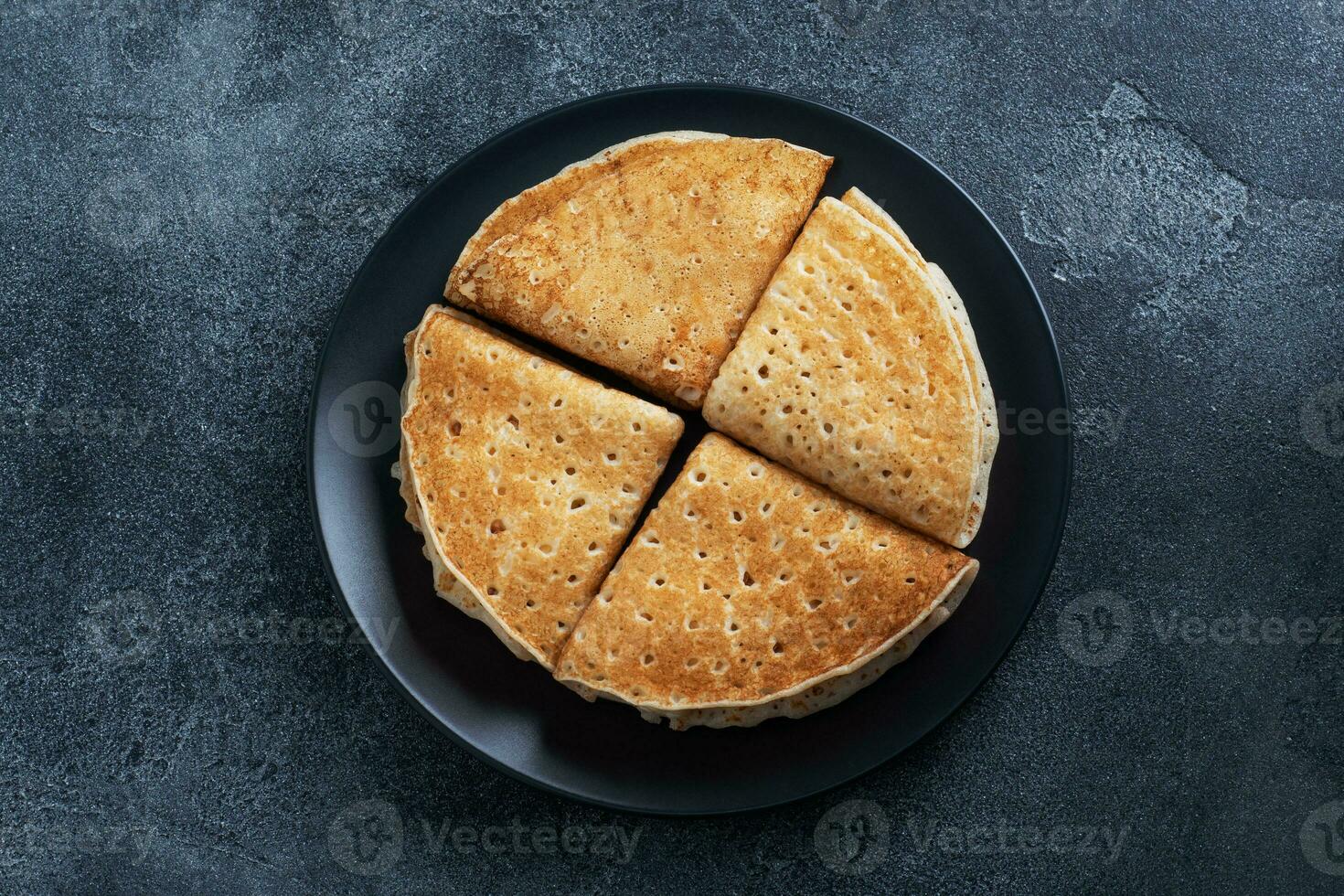 crêpes fourrées au chocolat et à la banane. délicieux petit déjeuner d'enveloppes de crêpes sur une assiette, fond de béton foncé. photo