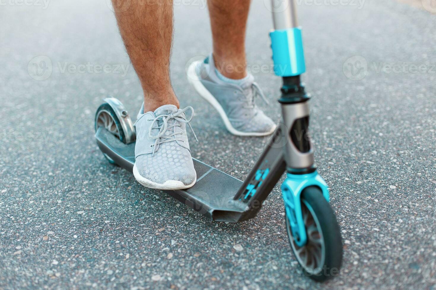 fermer de une scooter sur le asphalte. donner un coup scooter. homme équitation scooter photo