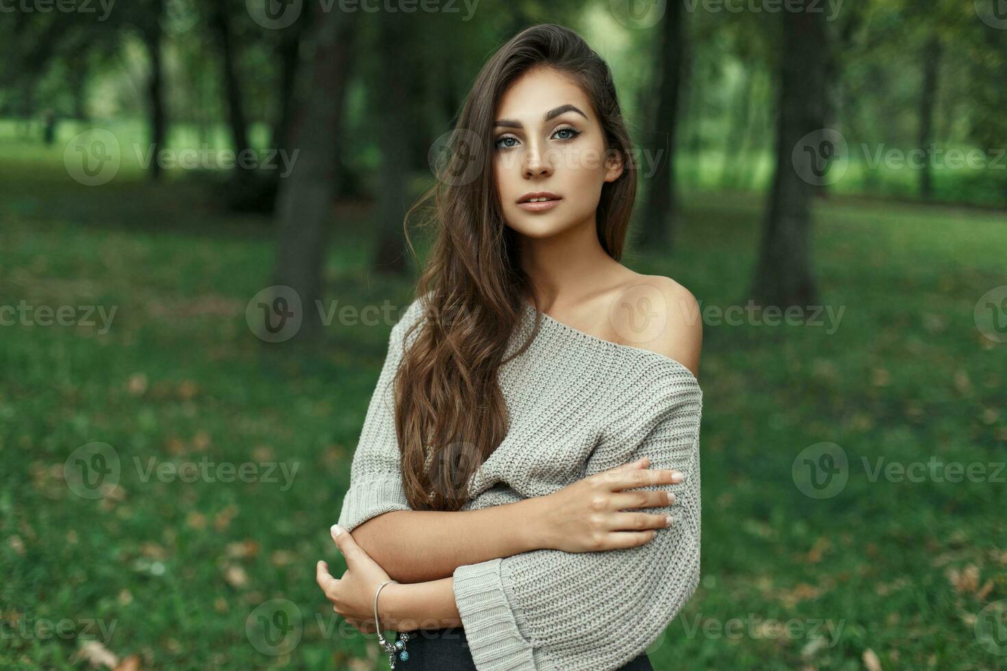 magnifique modèle femme dans ancien tricoté chandail avec nu épaules dans le parc à la recherche à le caméra photo