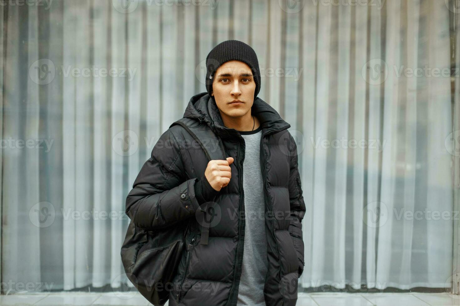 Beau Jeune homme dans hiver veste et tricoté noir chapeau sur ville  Contexte 23335648 Photo de stock chez Vecteezy