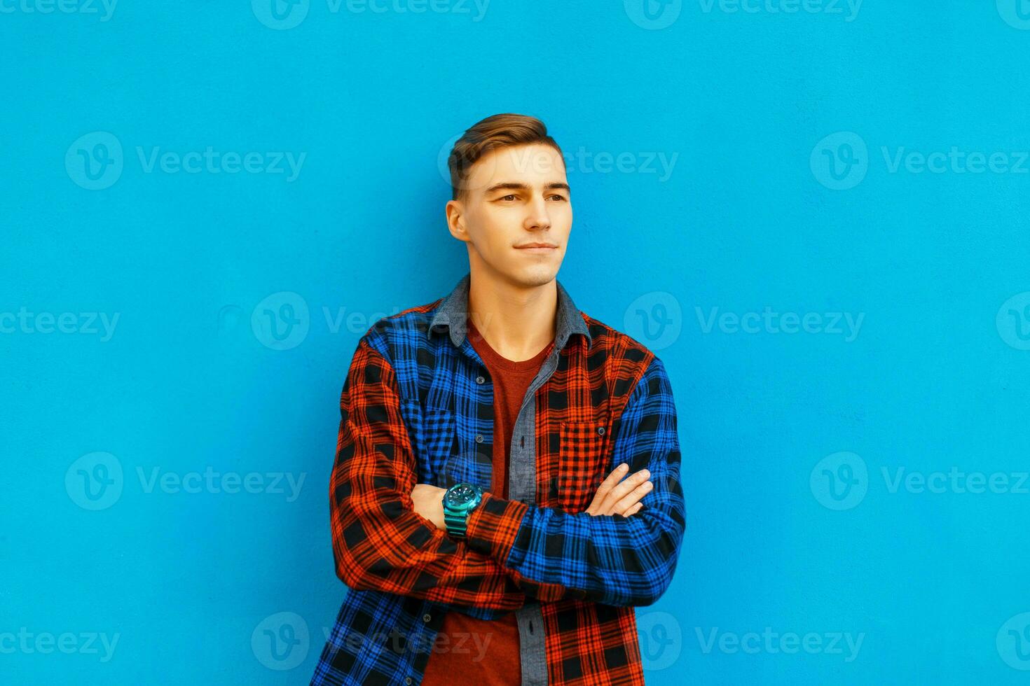 Beau Jeune homme dans élégant vêtements pose près une bleu mur photo