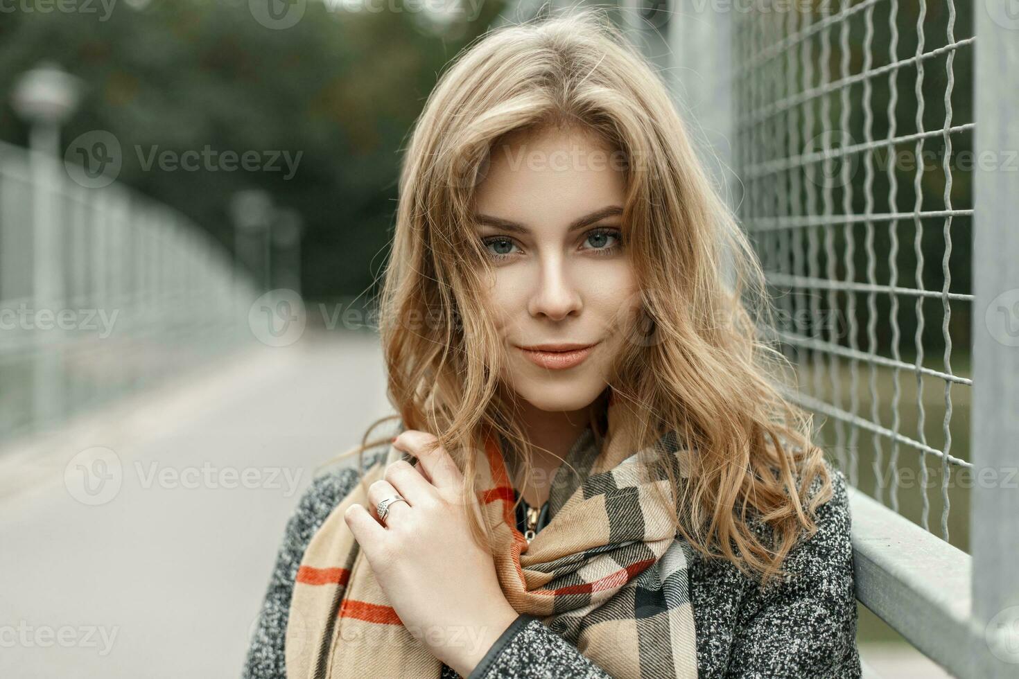 portrait de une magnifique Jeune blond femme dans l'automne ancien écharpe près métal grille photo