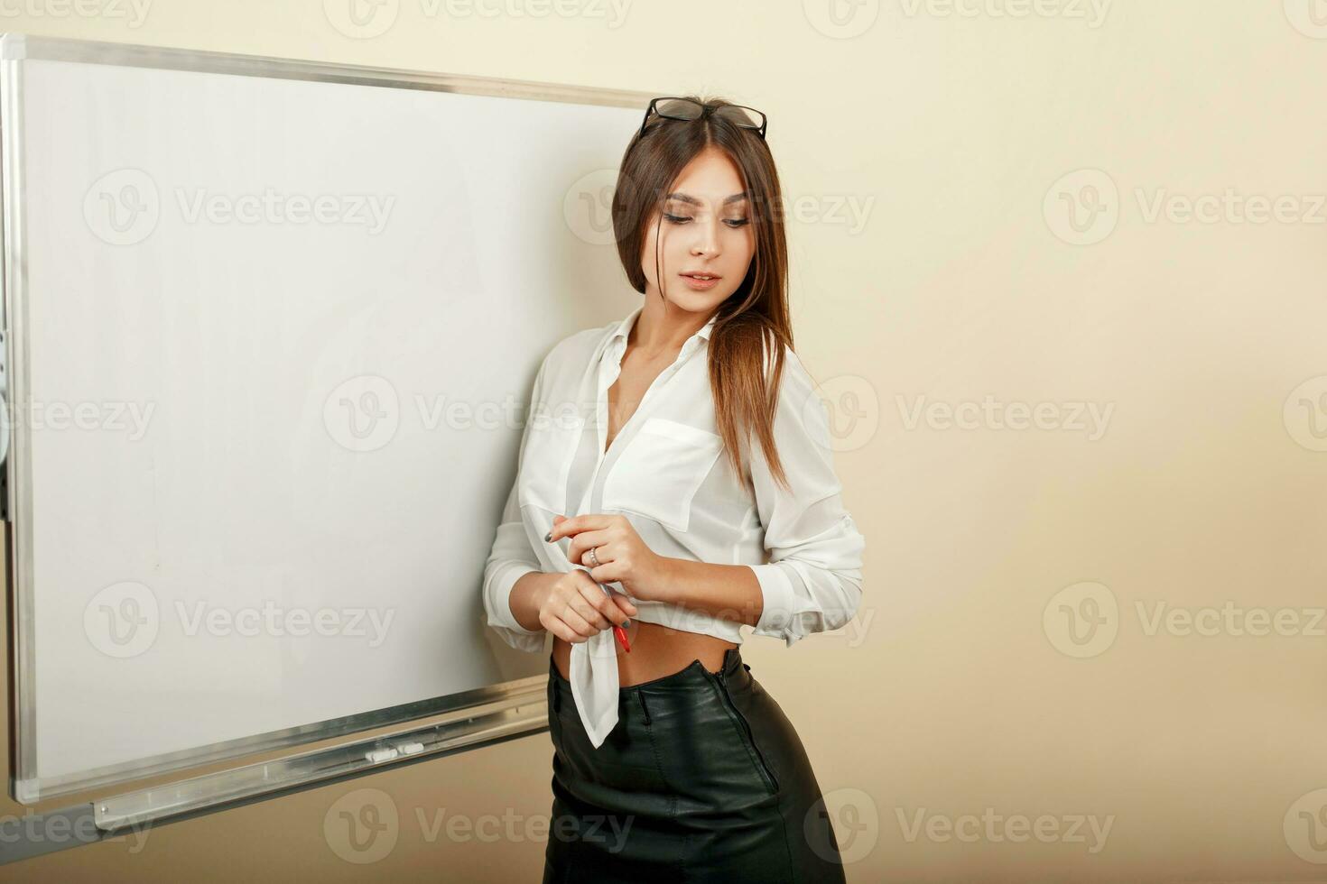 magnifique Jeune fille dans blanc chemisier et noir jupe permanent près une tableau blanc photo